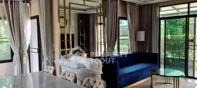 Luxurious living room with elegant decor and large windows offering garden views.