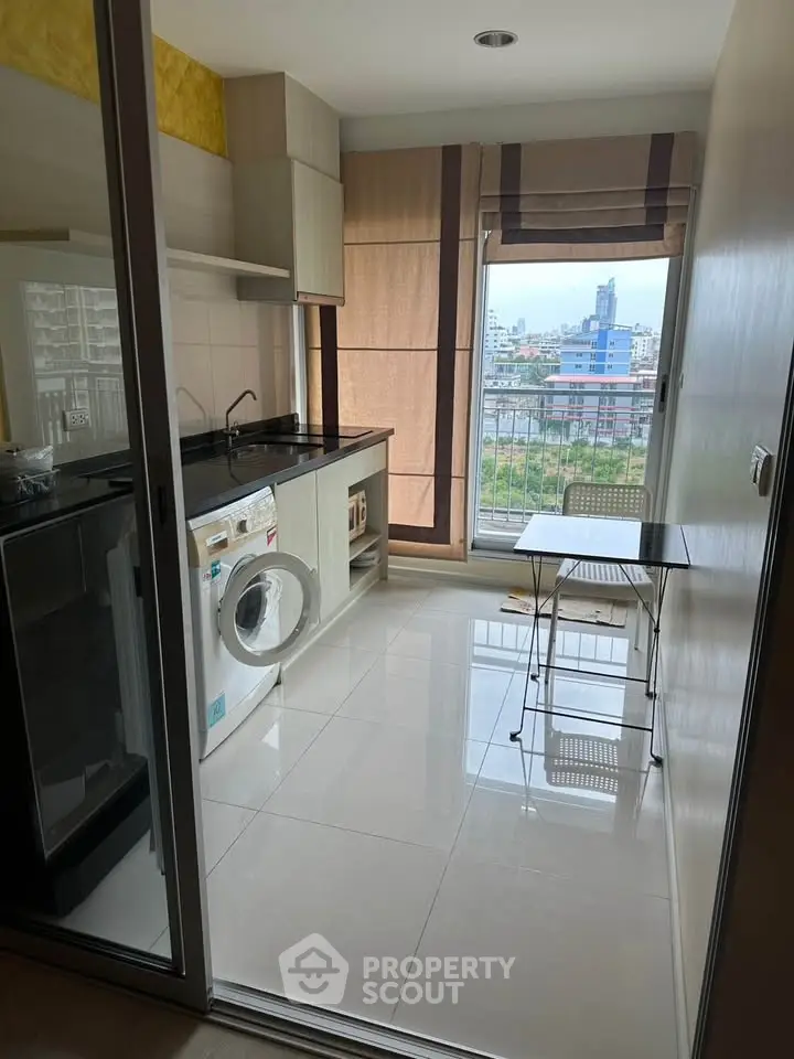 Modern kitchen with washing machine and city view from window, compact dining area.