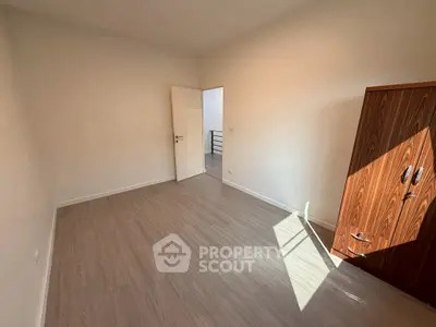 Spacious empty room with wooden flooring and wardrobe, perfect for customization.