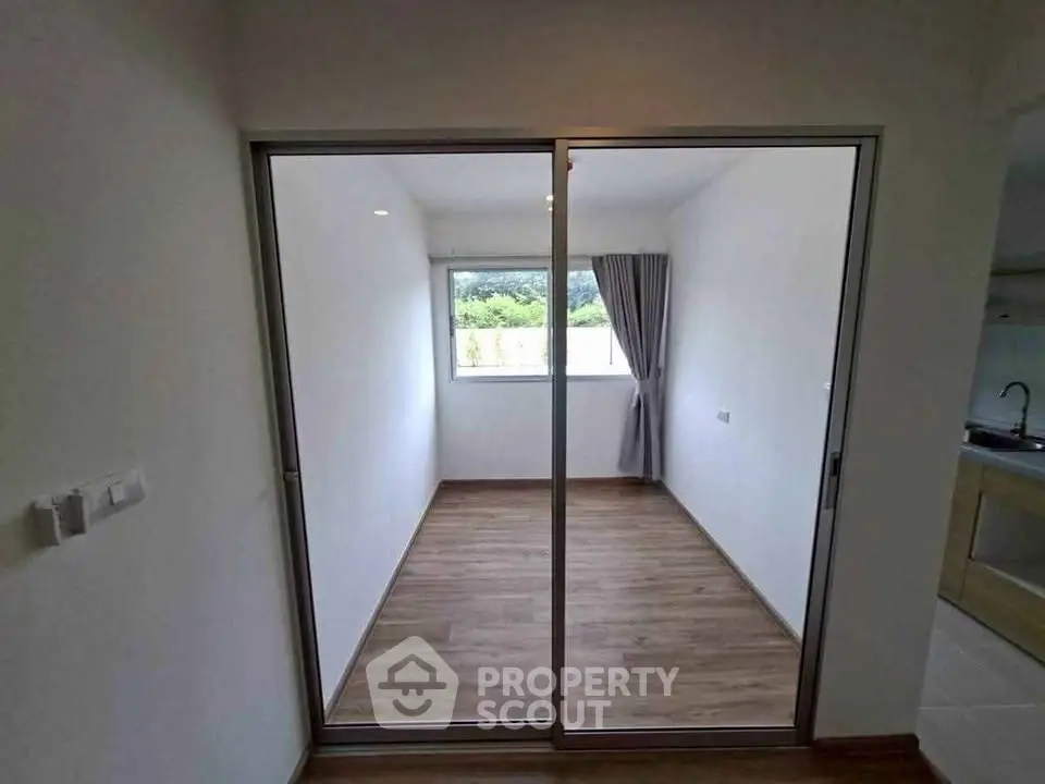 Spacious room with sliding glass doors and wooden flooring, ideal for versatile use.