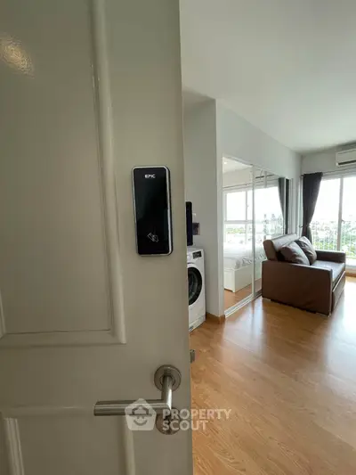 Modern apartment interior with smart lock, washing machine, and cozy living area with large windows.