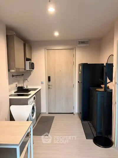 Modern compact kitchen with washing machine and fridge in cozy apartment.