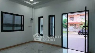 Spacious room with large windows and sliding glass door, offering ample natural light and modern design.