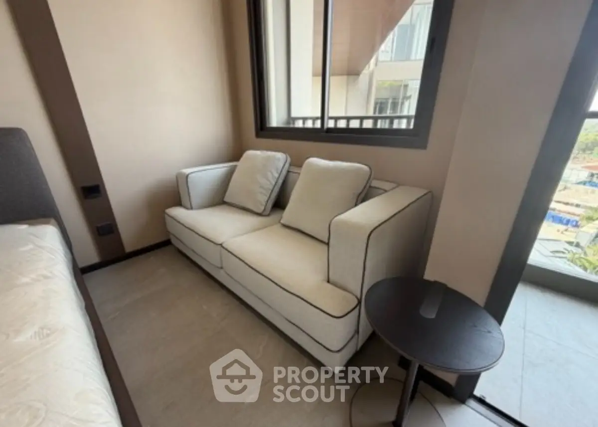 Cozy corner unit with stylish sofa and large windows offering natural light and urban views.