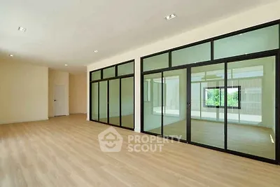 Spacious modern living room with large glass doors and wooden flooring.