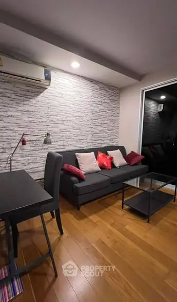Modern living room with stylish decor and wooden flooring, featuring a cozy sofa and sleek desk.