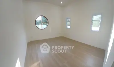 Spacious empty room with unique round window and natural light