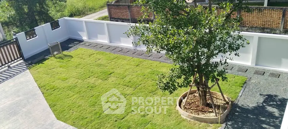 Spacious garden with lush green lawn and tree, perfect for outdoor relaxation.