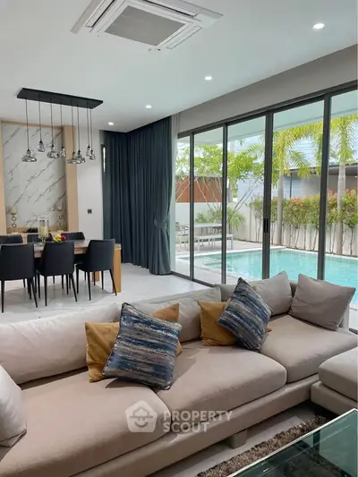 Luxurious living room with pool view, modern furniture, and elegant dining area in a contemporary home.