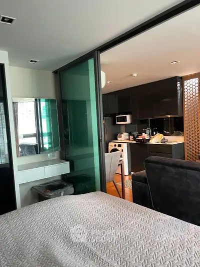 Modern studio apartment with sleek kitchen and cozy living area, featuring contemporary design and stylish furnishings.