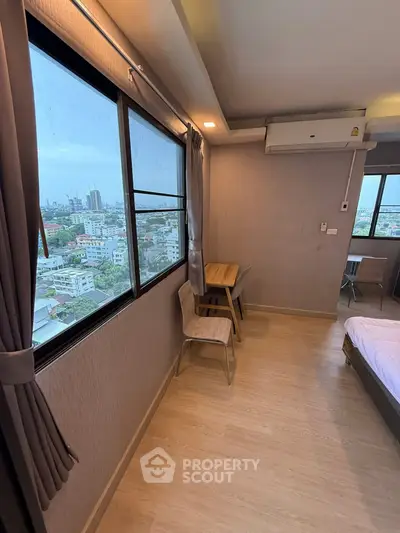 Modern bedroom with city view, featuring wooden flooring and air conditioning.