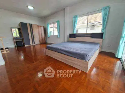 Spacious bedroom with wooden flooring and large windows in a modern home.