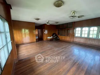 Spacious wooden-floored room with vintage charm and ample natural light from large windows.