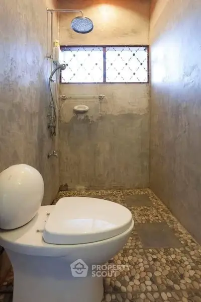 Rustic bathroom with stone flooring and modern showerhead