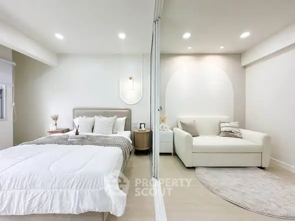 Modern bedroom with cozy living area, featuring elegant decor and neutral tones.
