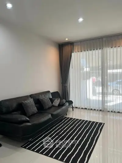 Modern living room with sleek black leather sofa and striped rug