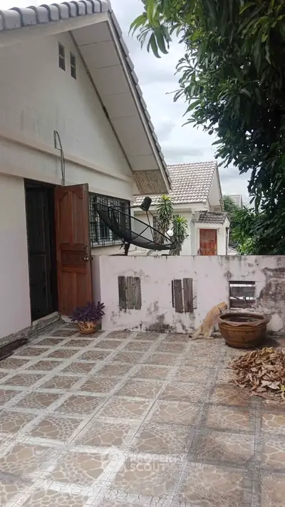 Charming residential exterior with tiled patio and lush greenery, perfect for outdoor relaxation.