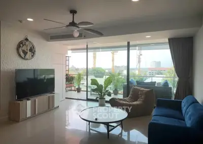 Spacious living room with modern decor and large balcony offering city views.