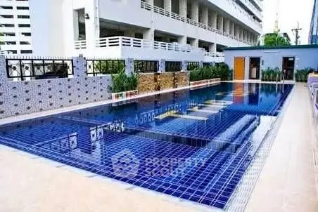 Luxurious outdoor pool area with modern design and vibrant blue tiles in a residential complex.
