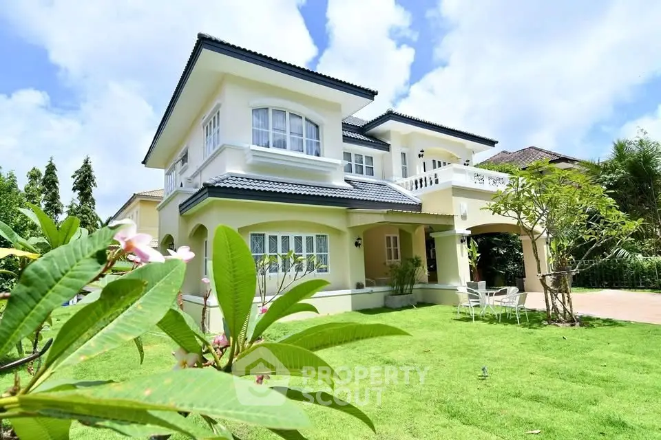 Stunning two-story house with lush garden and elegant architecture under a clear blue sky.