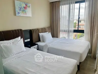 Bright and cozy bedroom with twin beds and large window offering city views.