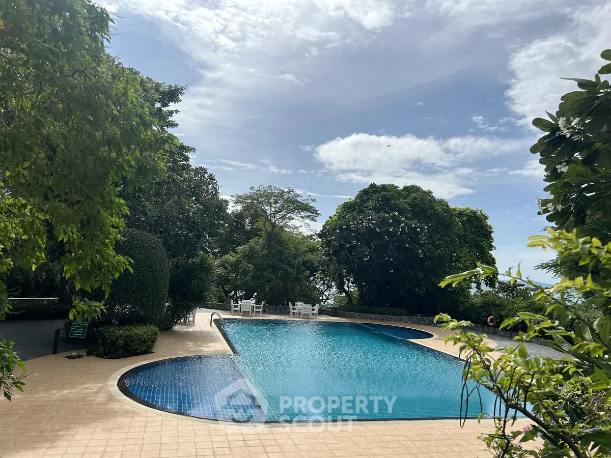 Luxurious outdoor pool surrounded by lush greenery and serene sky views, perfect for relaxation and leisure.