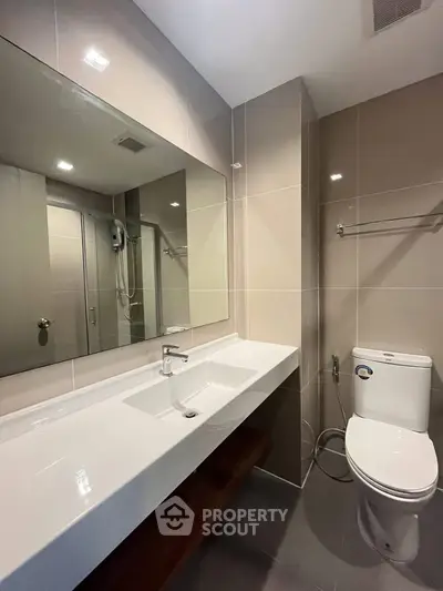 Modern bathroom with sleek fixtures and large mirror in a contemporary home.