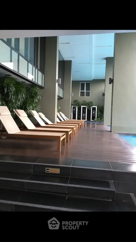 Luxurious poolside area with modern lounge chairs and lush greenery in a high-end residential complex.