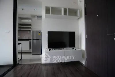 Modern apartment interior with sleek kitchen and stylish living area featuring a flat-screen TV.