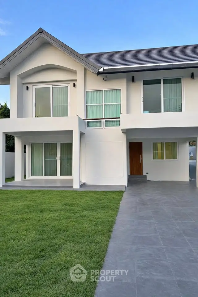 Modern two-story house with large windows and spacious driveway