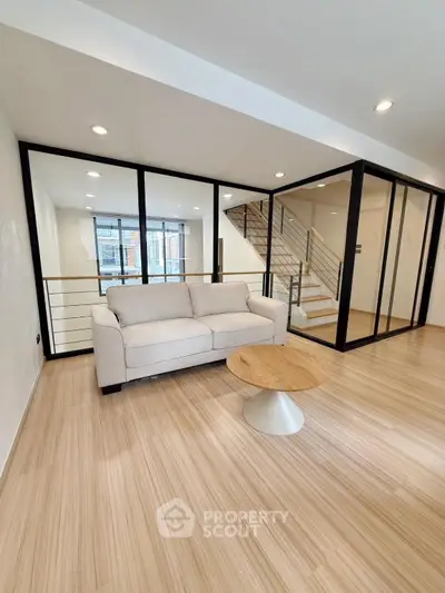 Modern living room with glass partitions and wooden flooring in a stylish apartment.