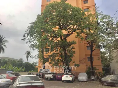 Spacious parking area with lush greenery and a tall residential building.