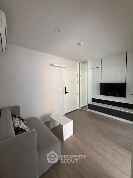 Modern living room with sleek design, featuring a wall-mounted TV and stylish furniture.