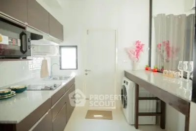 Modern kitchen with sleek cabinets and washing machine, featuring bright natural light.