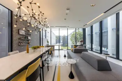 Modern living room with stylish lighting and large windows overlooking a garden.