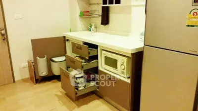 Modern kitchen with open cabinets and microwave in compact apartment.