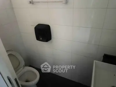 Compact bathroom with white tiles and modern fixtures, ideal for efficient space utilization.