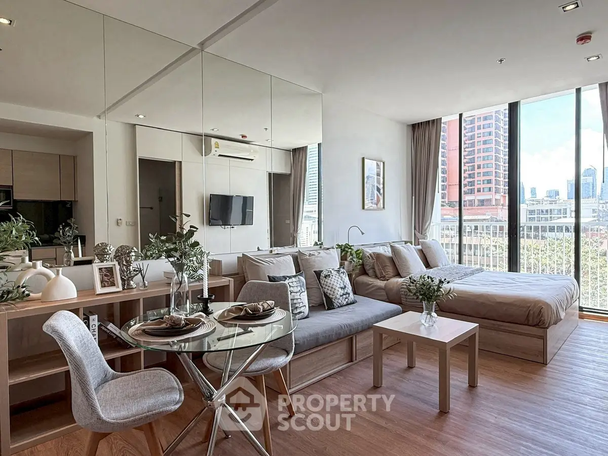Modern open-plan living room with dining area and city view, featuring stylish decor and natural light.