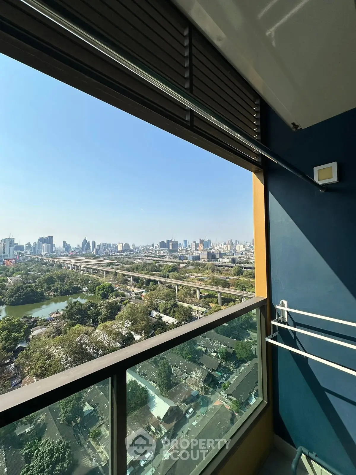 Stunning cityscape view from a high-rise balcony with clear blue skies.