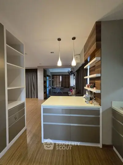 Modern open-plan living space with stylish shelving and pendant lighting