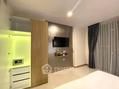 Modern bedroom with sleek TV setup and ambient lighting in a stylish apartment.