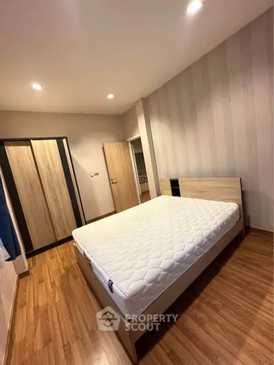 Spacious bedroom with wooden flooring and modern wardrobe in a stylish apartment.