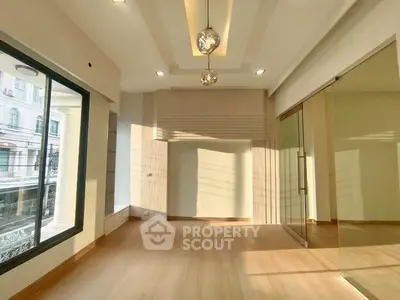 Spacious modern room with large windows and elegant lighting, perfect for versatile living or office space.