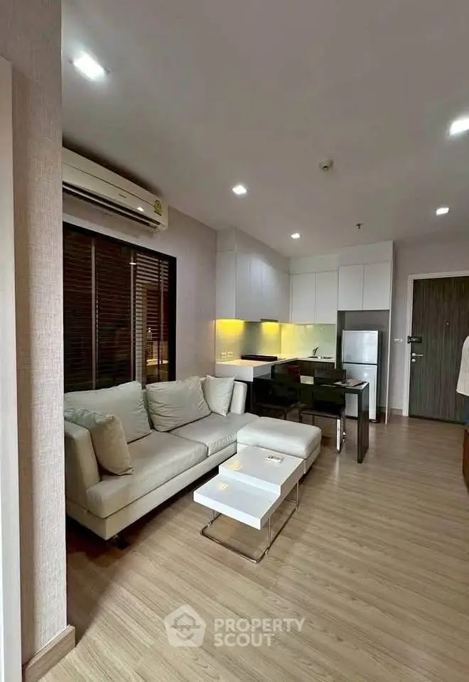 Modern living room with open kitchen, featuring sleek furniture and wooden flooring in a stylish apartment.