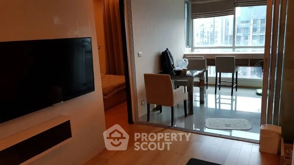 Modern apartment interior with open living and dining area, featuring large windows and stylish furniture.