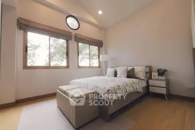 Spacious bedroom with elegant decor and large windows for natural light.