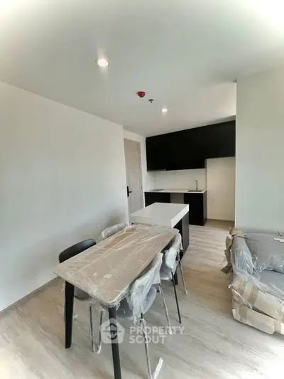 Modern open-layout kitchen and dining area with sleek black cabinets and natural light.