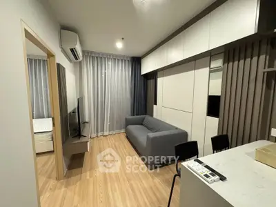 Modern living room with sleek design and open layout, featuring a cozy gray sofa and wall-mounted TV.