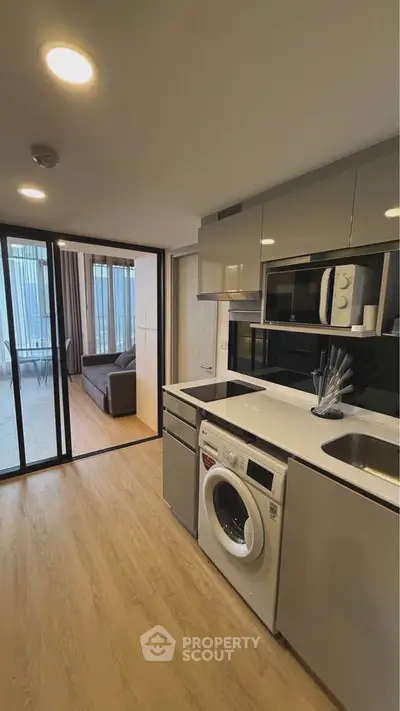 Modern kitchen with washing machine and open layout leading to living area