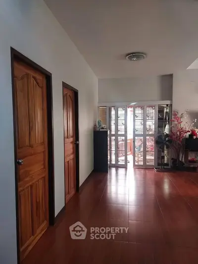 Spacious hallway with wooden doors and natural light from large windows.